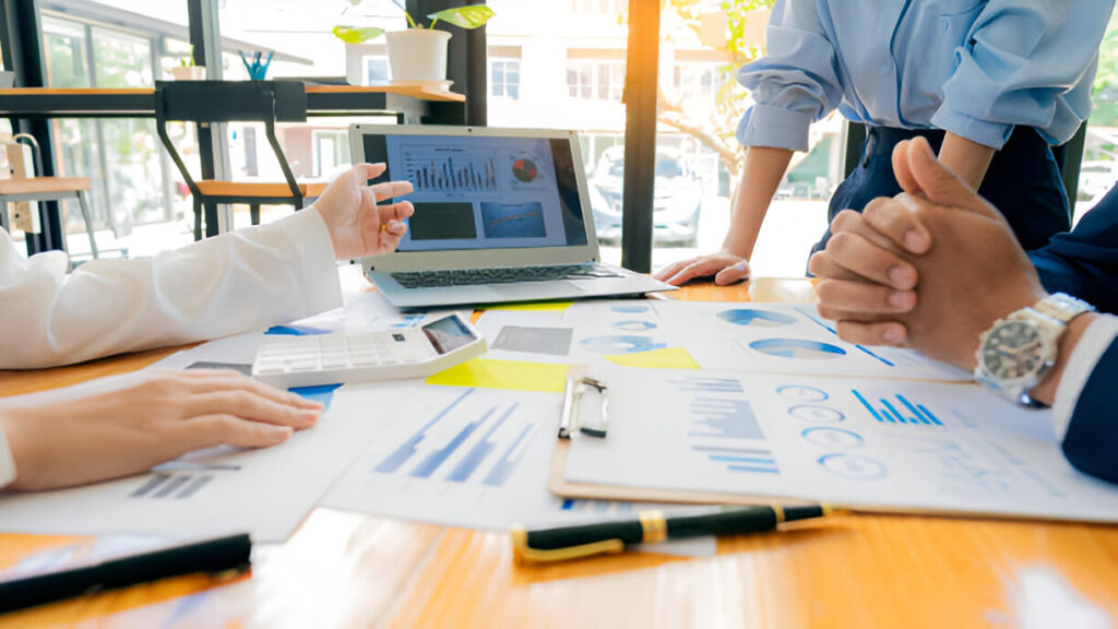 Diverse sales team collaborating on strategy in a modern meeting room discussing sales compensation plans
